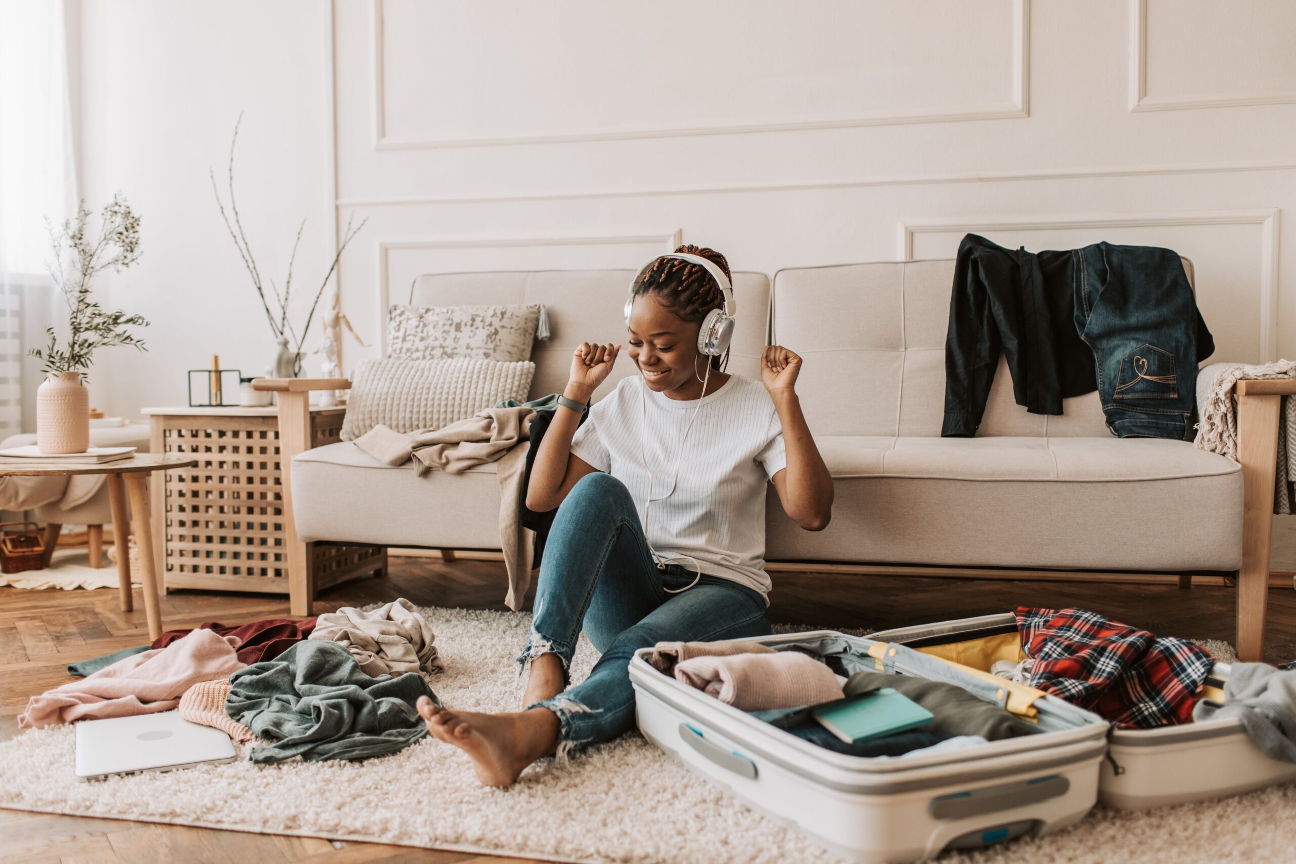 girl smiling and listening to music while packing suitcase